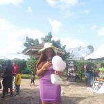 A lady wearing a purple dress holding a cotton candy at an event at the Nelson Mandela Gardens and resorts, Asaba