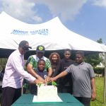 A boy cutting a cake with Dr Newton Jibunoh seen in the group of picture